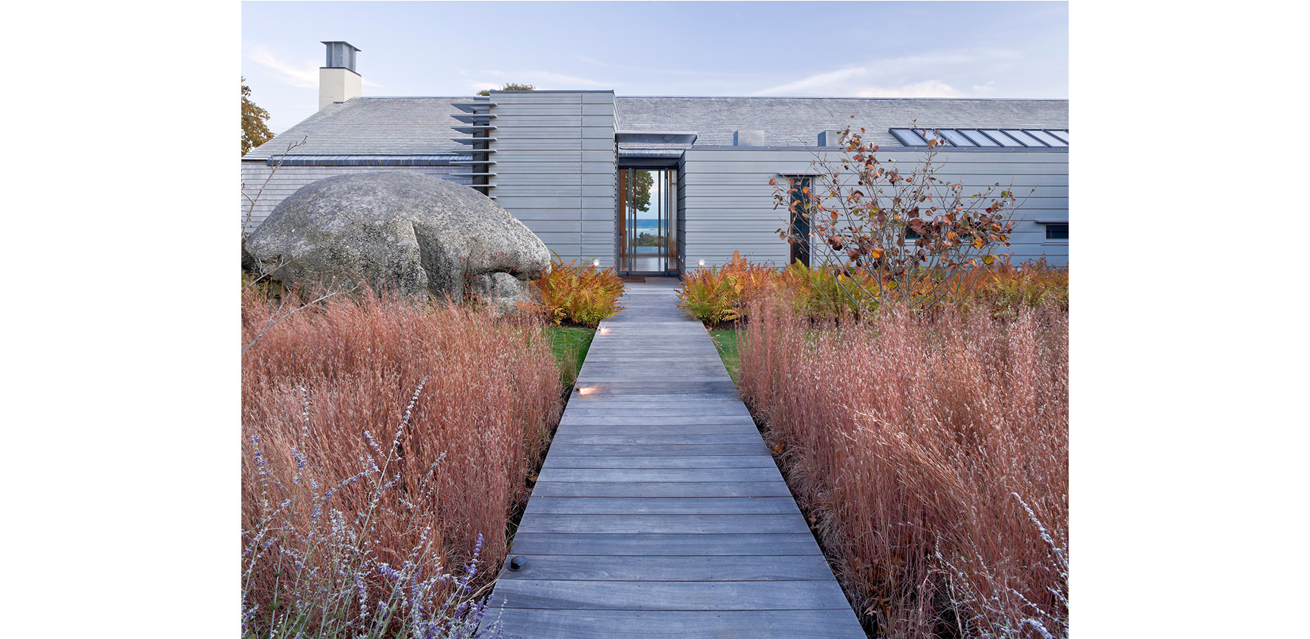 House Exterior with Cinammon Ferns, Bluestem Grasses, and a Granite Boulder