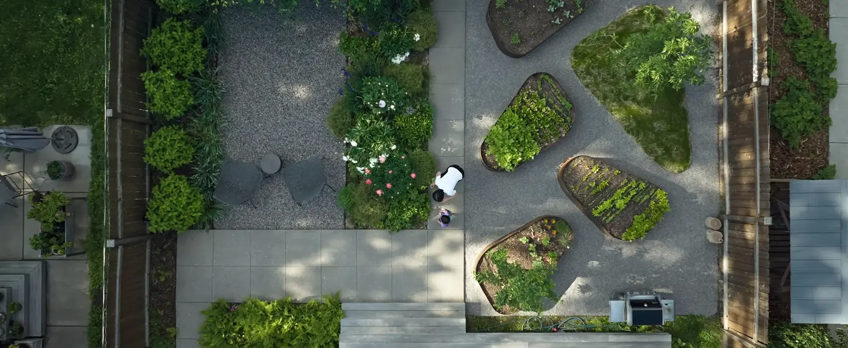 Aerial view of backyard designed as a space for family gatherings, outdoor dining, play, and shared gardening experiences